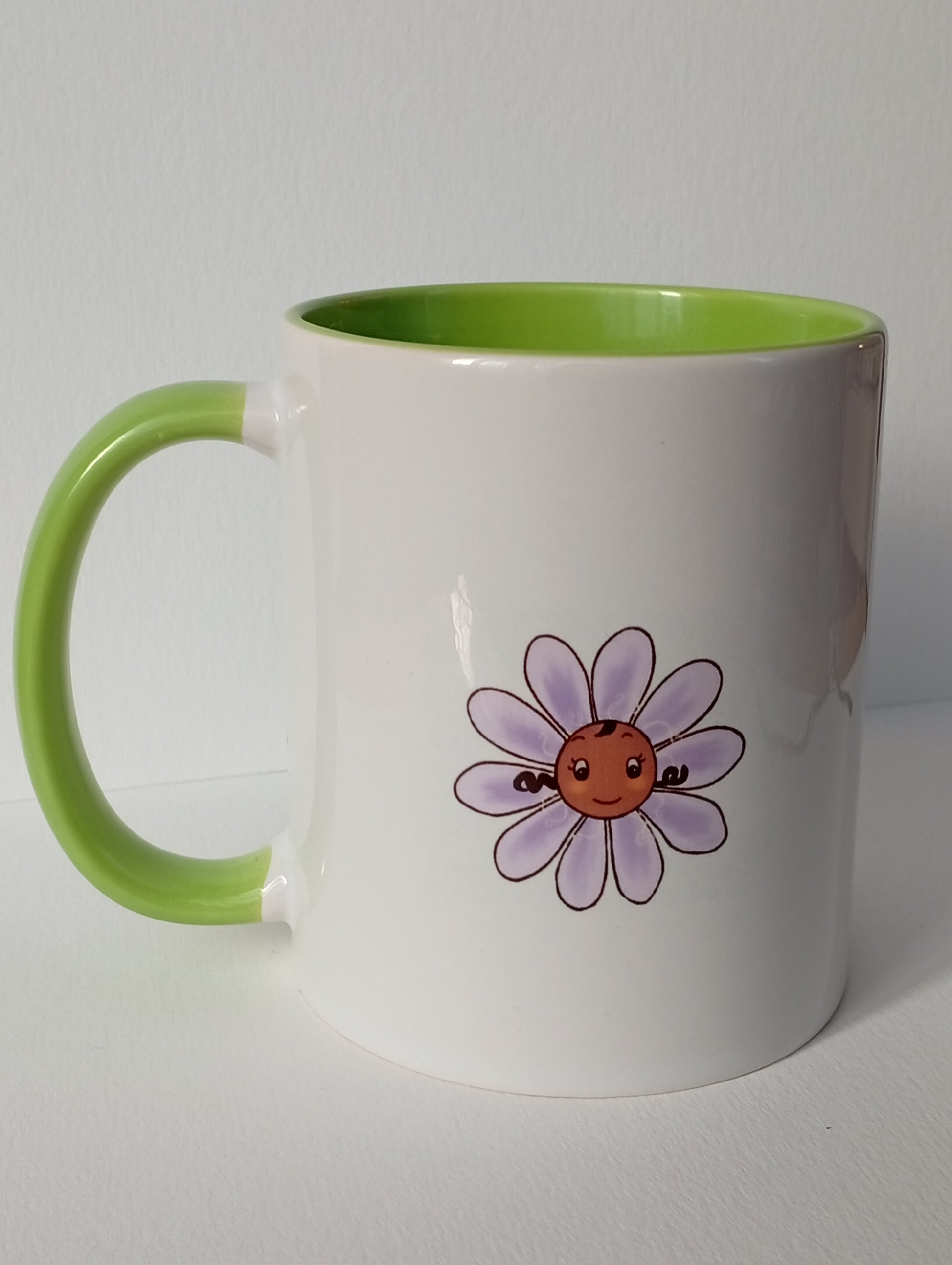 White mug with light green handle and interior, featuring a smiling violet flower illustration