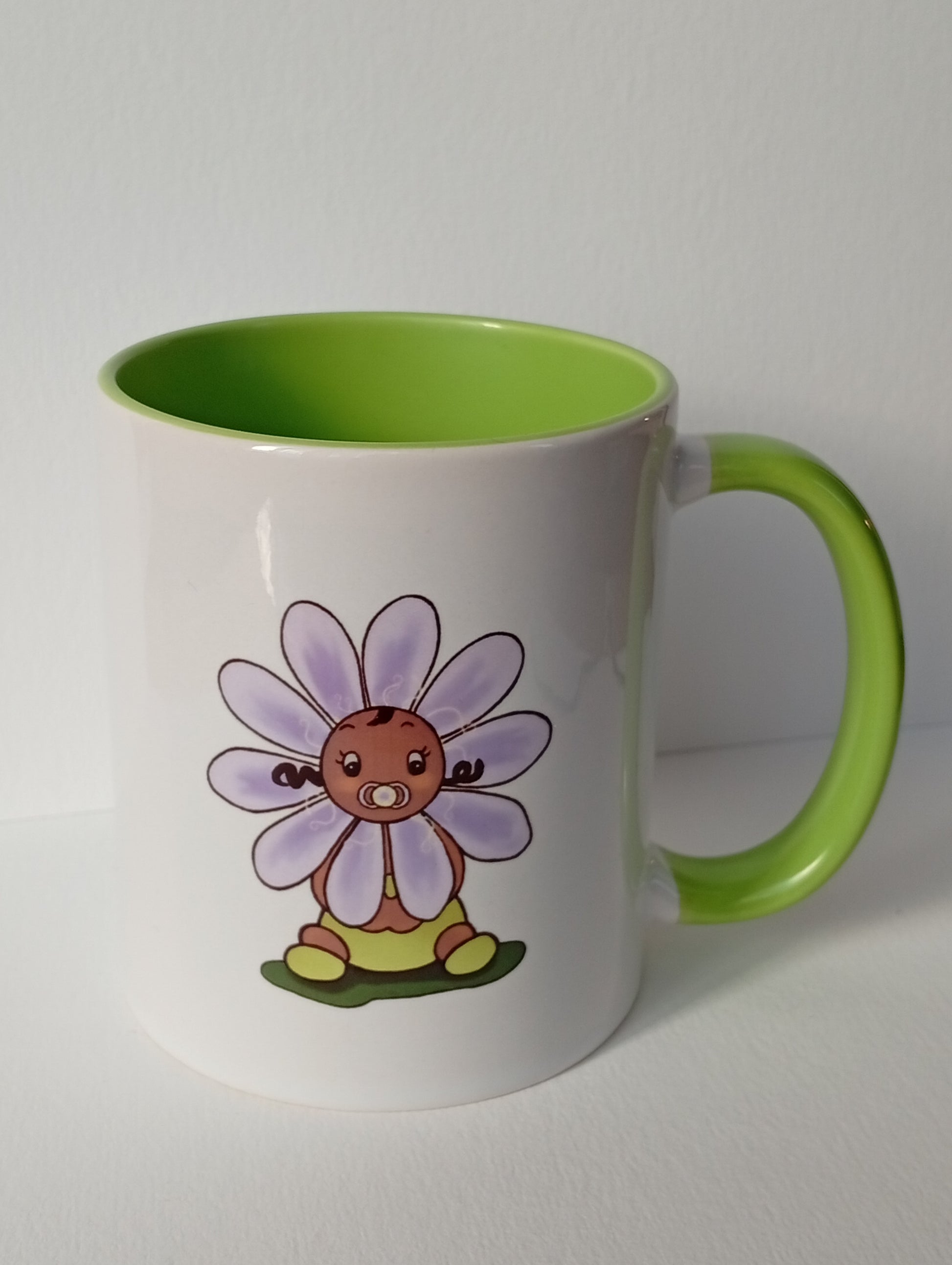 White mug with green handle and inside, featuring a cute violet flower baby illustration