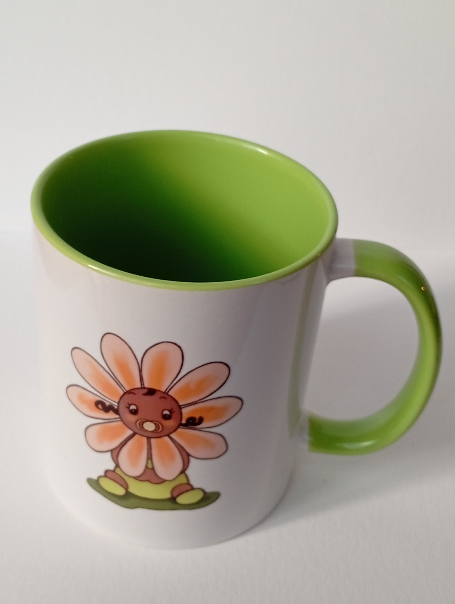 White and green mug with cute flower baby cartoon design on a plain background