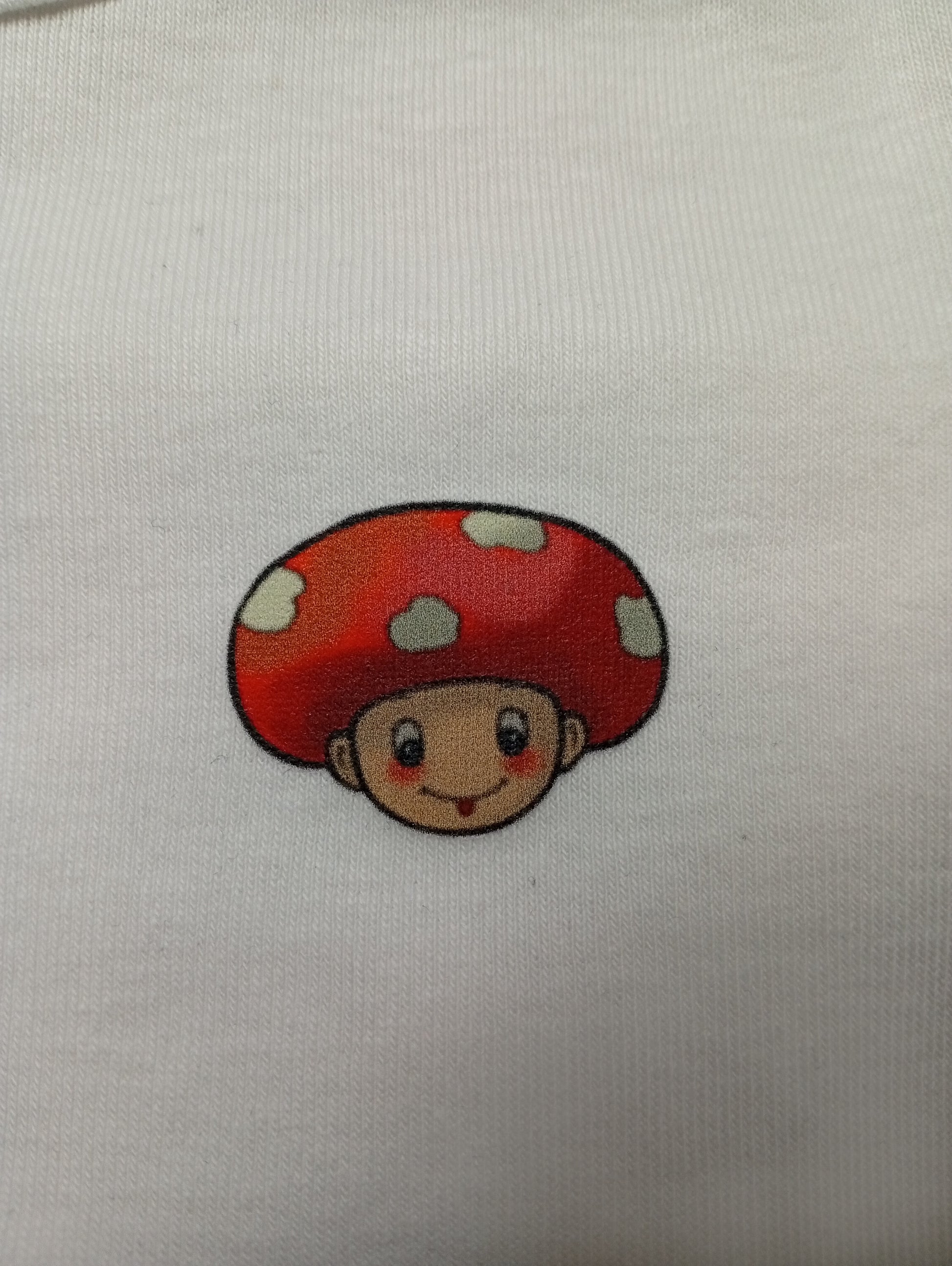Cartoon mushroom head character with red cap on white fabric background